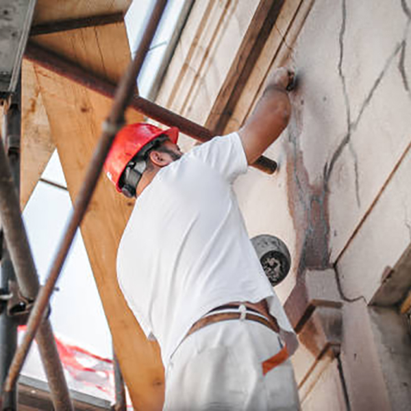Man worker standing on scaffolding, perform work on the restoration of the facade of the old building. Repairing and renovate